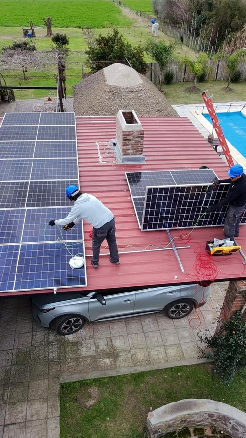 Instaladores colocando paneles solares sobre un techo de chapa colorada
